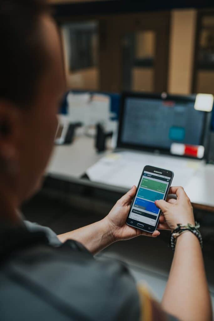 A person in an office setting is using a cell phone while seated at a desk.