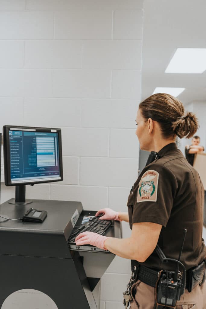 A woman in uniform is focused on using a computer at her workstation.